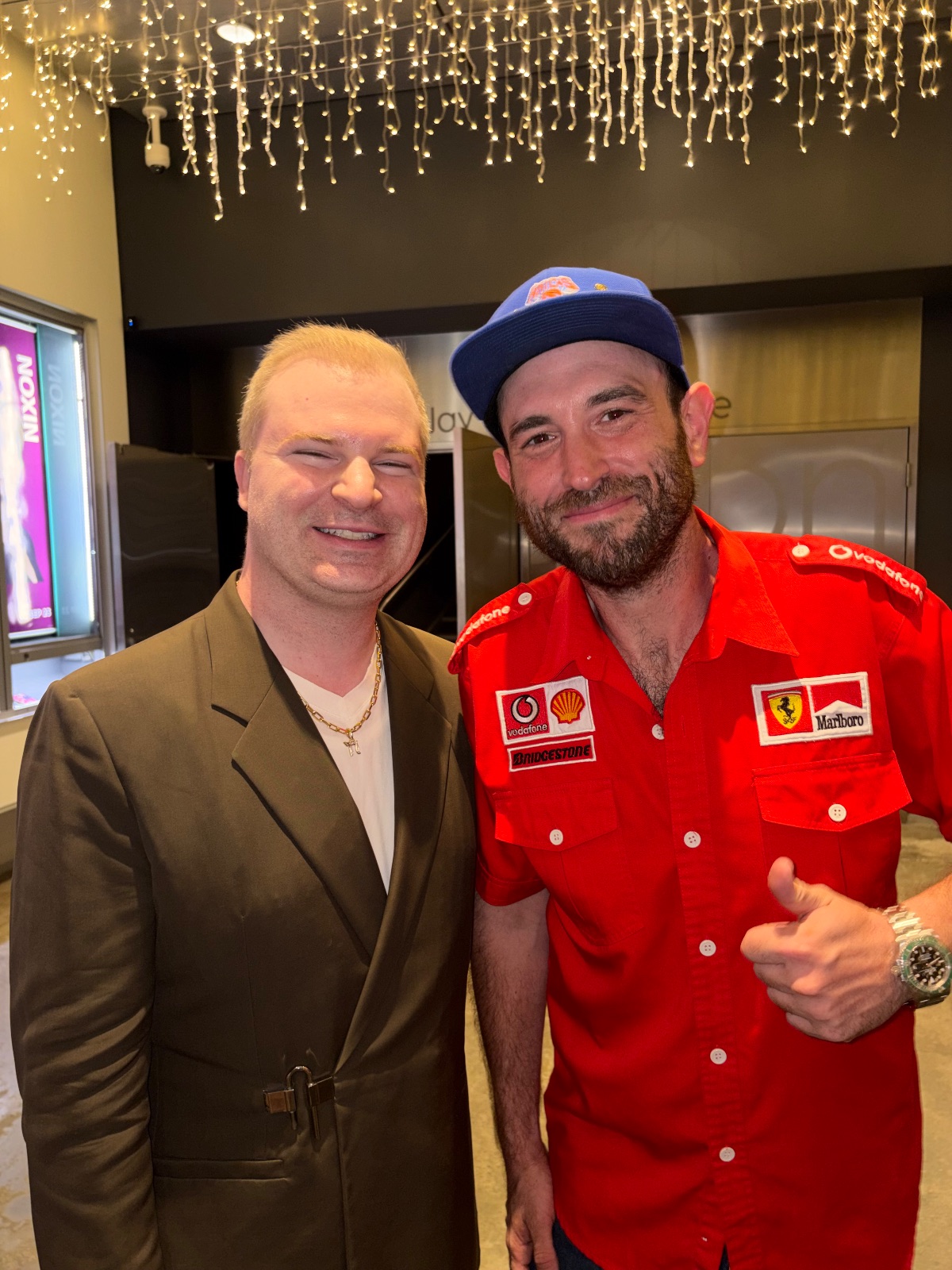 Two people smiling at the camera while posing together for a photo at what appears to be a social gathering or event.
