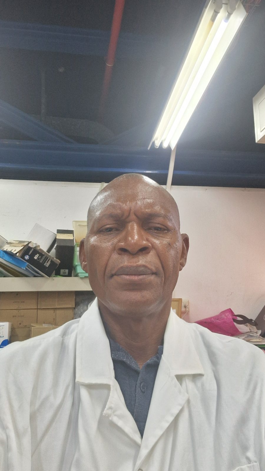A healthcare professional in a white lab coat poses in a clinical laboratory workspace.