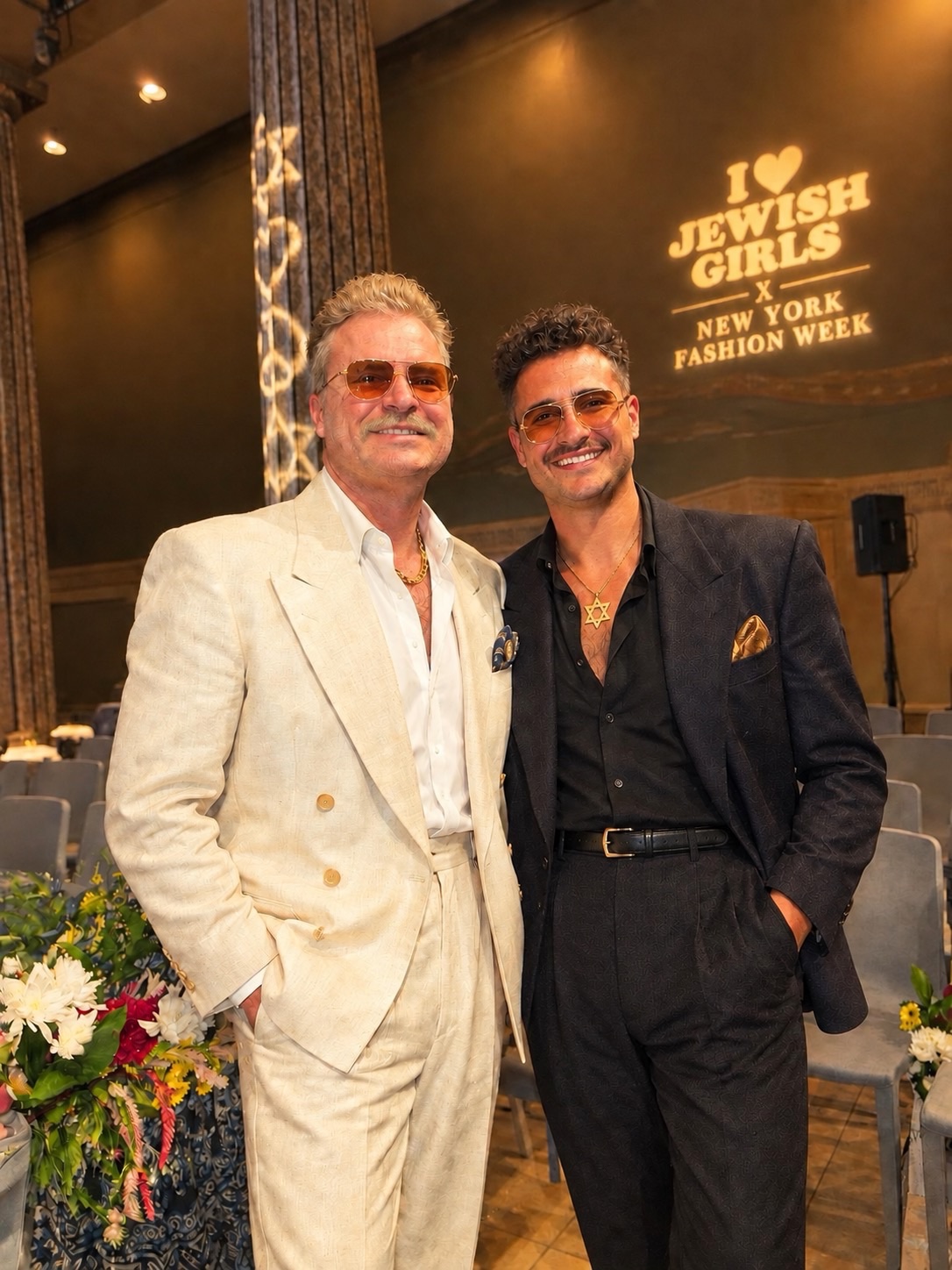 Two elegantly dressed people smile at a formal gala event.